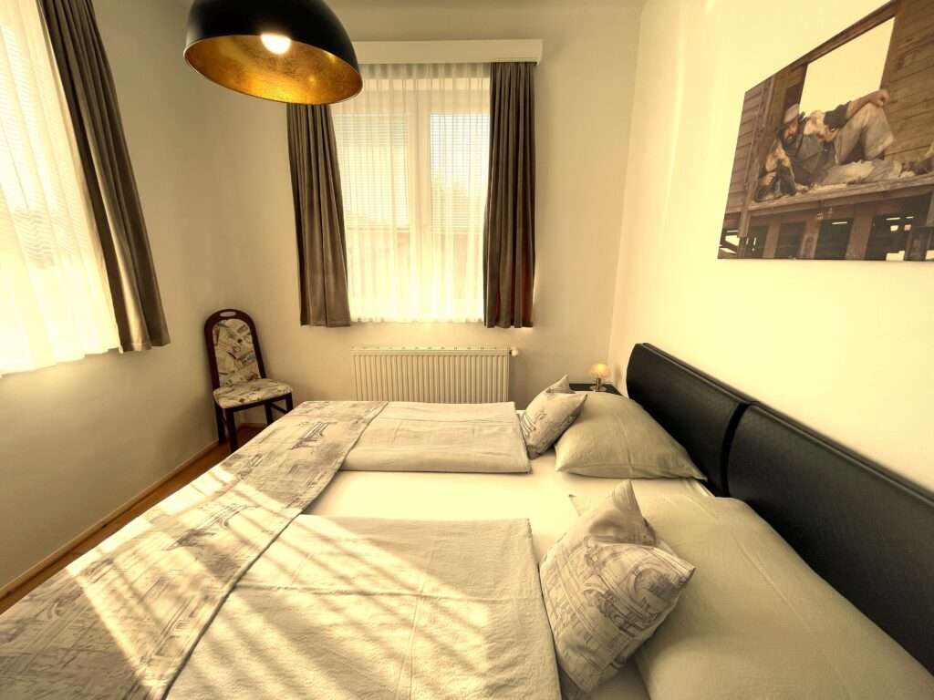 Schlafzimmer mit schwarzem Lederbett, Sessel in der Ecke und Bud Spencer als Bild an der Wand